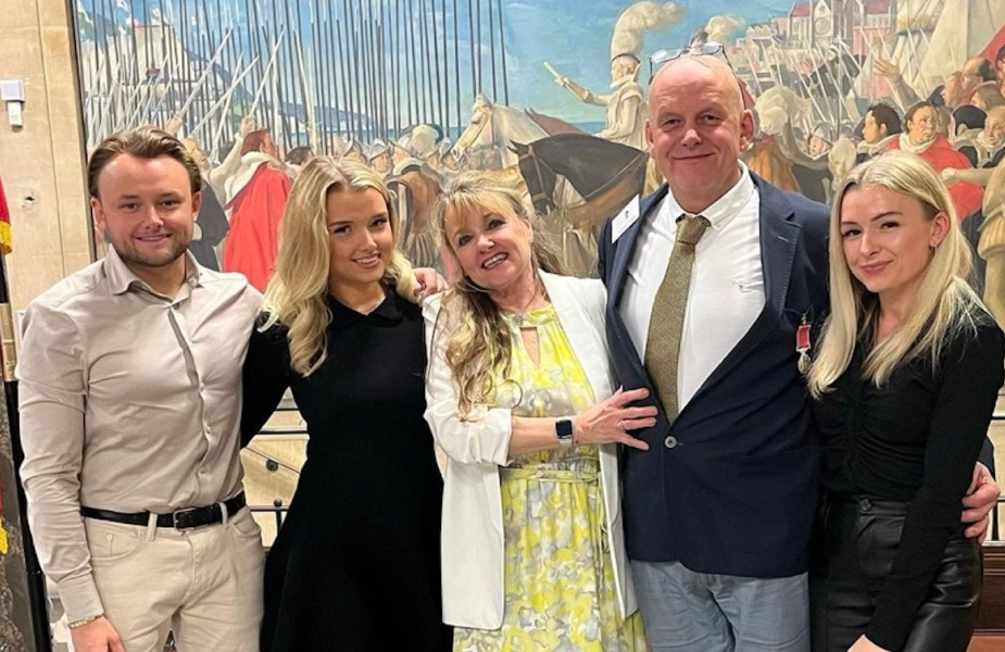 A group of people posing for a picture in front of a painting.